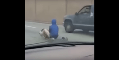 Watch man riding big wheel dodge cars on Philly highway