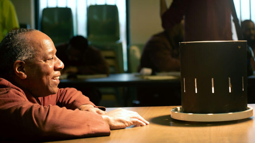 Incarcerated artist Ezra watches his animation play on a cylinder.