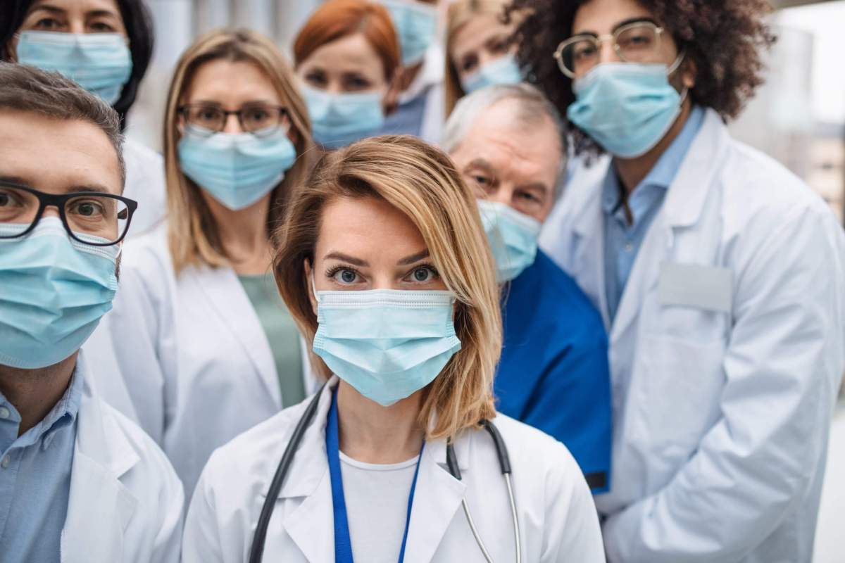 Group of doctors with face masks looking at camera, corona virus concept.