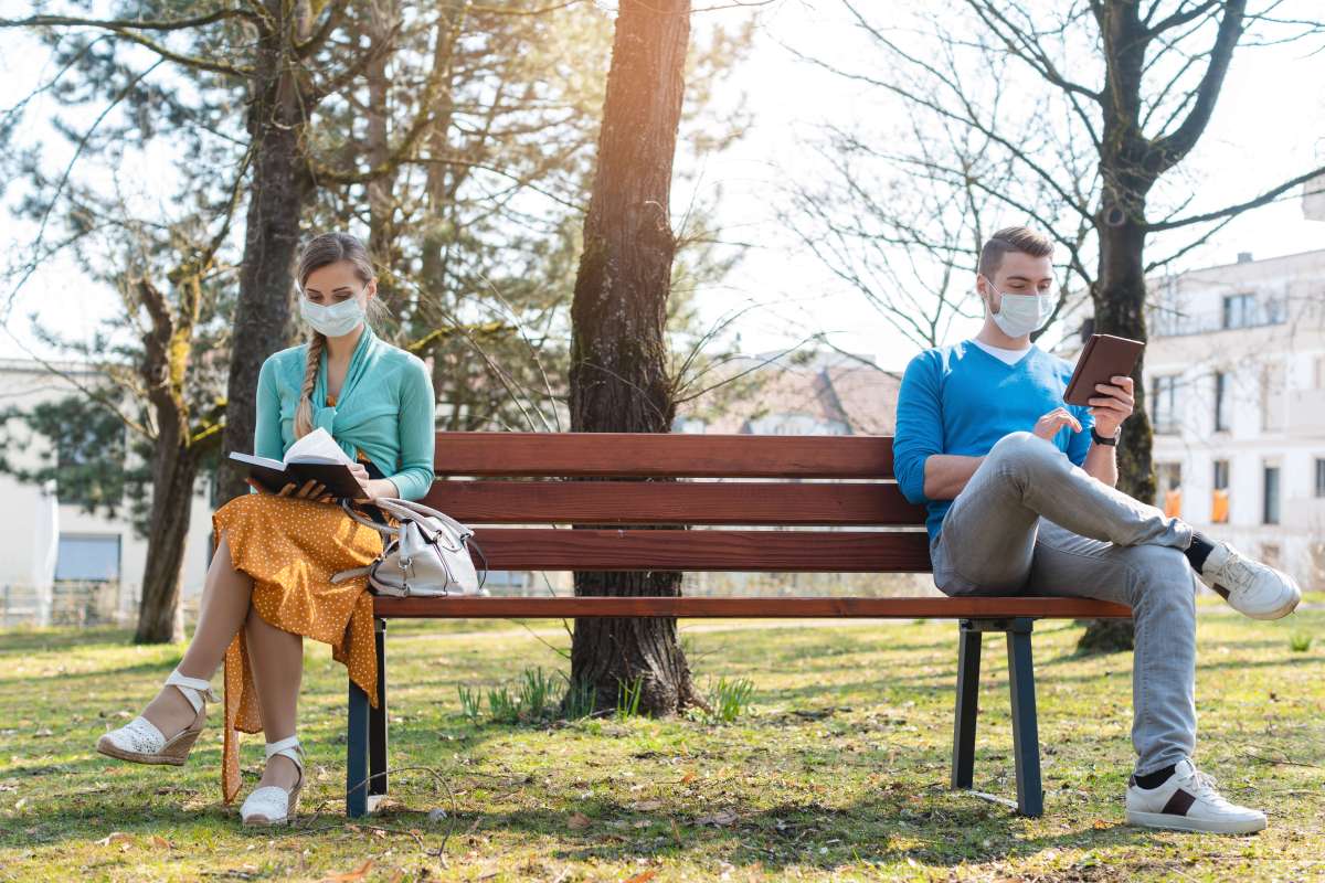 Woman and man in social distancing sitting on bench