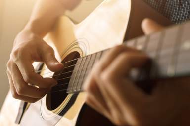 Man’s hand playing acoustic guitar