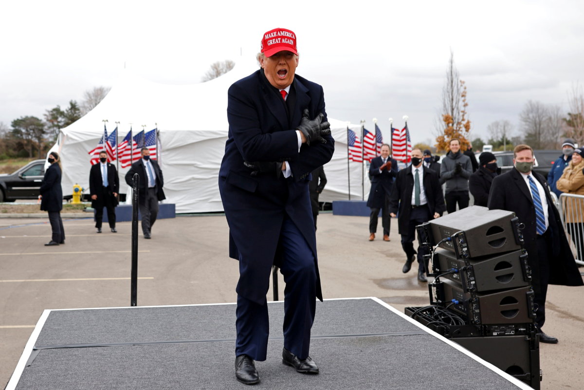 U.S. President Donald Trump reacts to cold weather and wind during a campaign rally at Michigan Sports Stars Park in Washington