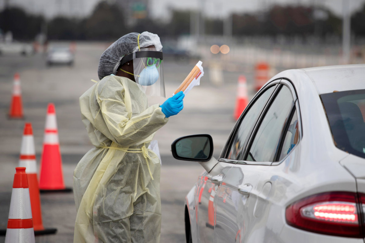 FILE PHOTO: A healthcare worker holds a coronavirus disease (COVID-19) informational pamphlet for a resident at a drive-thru testing location in Houston