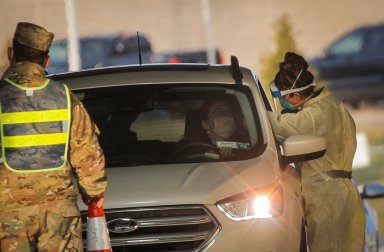 A health worker provides a COVID-19 test at a drive-through testing site, in Staten Island, New York