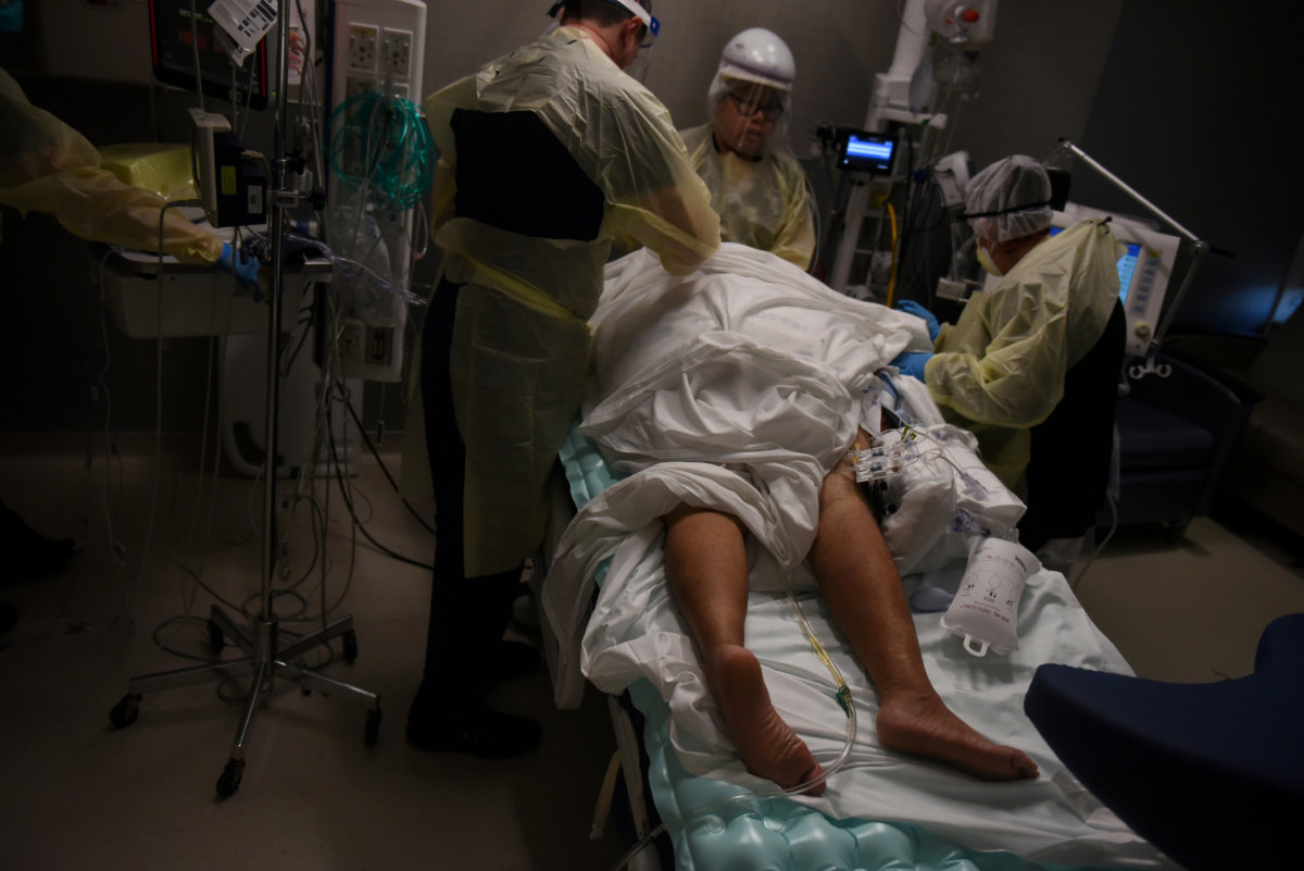 FILE PHOTO: Healthcare personnel work with a patient inside a room for people with coronavirus disease (COVID-19) at a hospital in Hutchinson