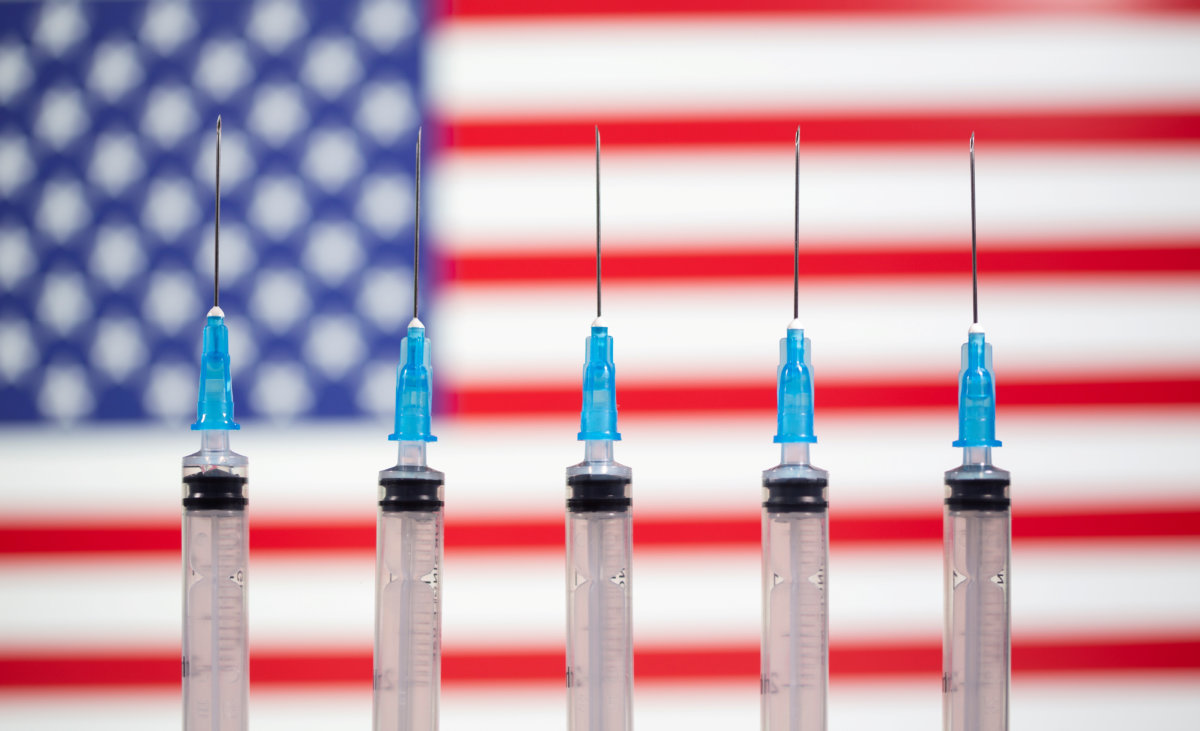 FILE PHOTO: Syringes are seen in front of a displayed U.S. flag in this illustration