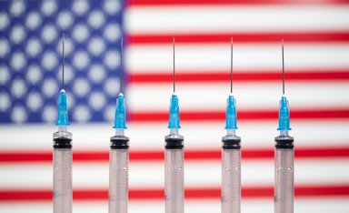 FILE PHOTO: Syringes are seen in front of a displayed U.S. flag in this illustration