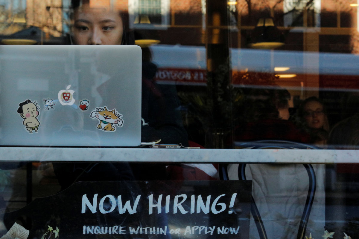 FILE PHOTO: A “Now Hiring” sign sits in the window of Tatte Bakery and Cafe in Cambridge