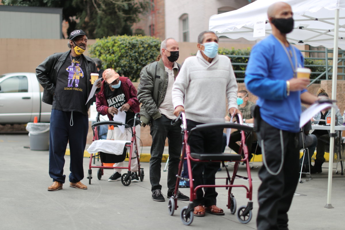 People queue to receive coronavirus disease (COVID-19) vaccinations at the LA Mission homeless shelter on Skid Row, in Los Angeles