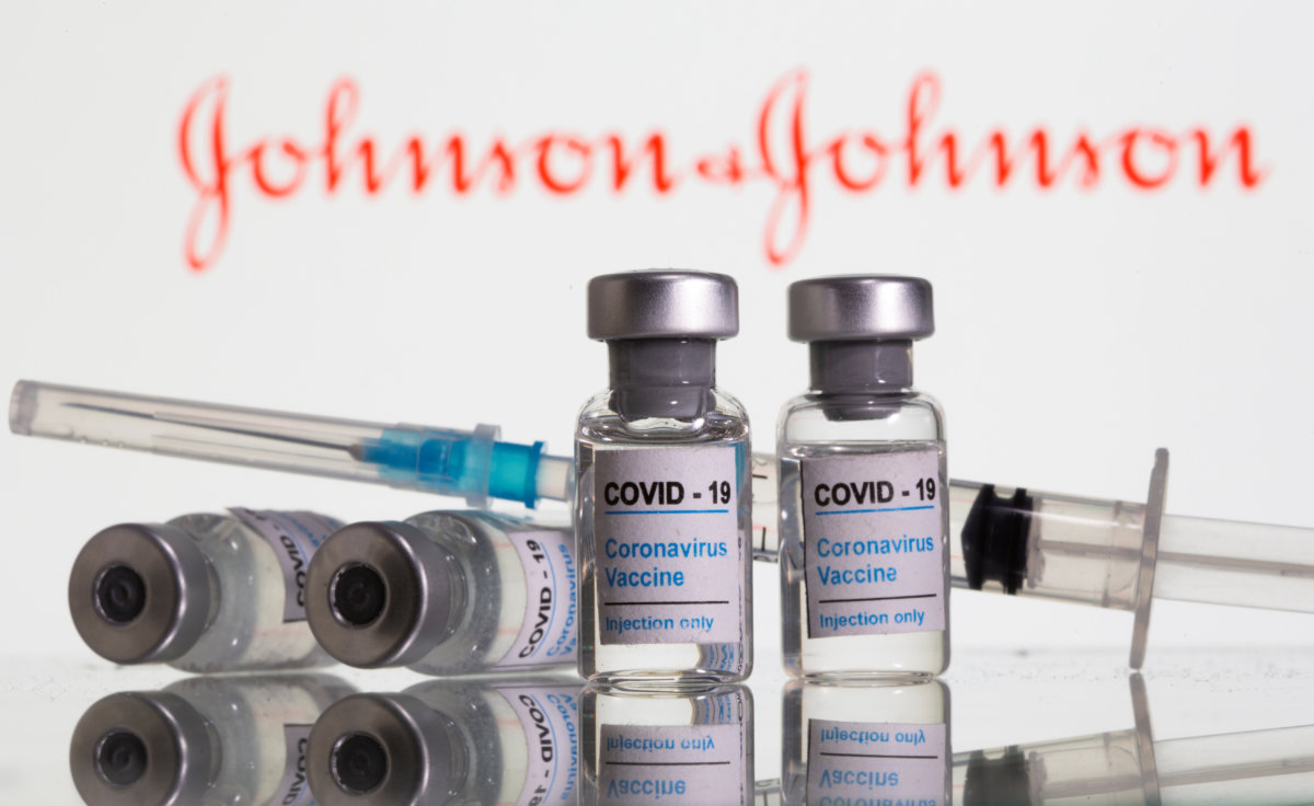 FILE PHOTO: Vials labelled “COVID-19 Coronavirus Vaccine” and sryinge are seen in front of displayed J&J logo in this illustration