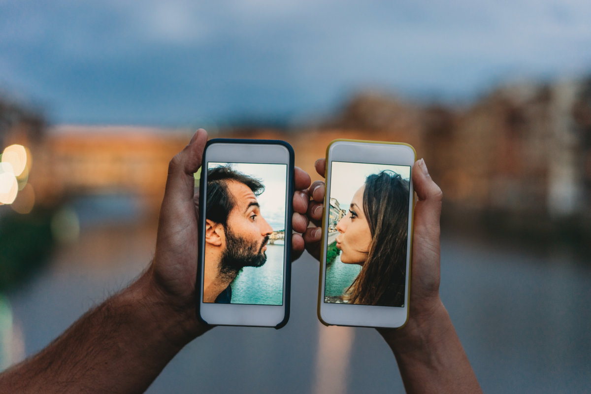Young couple kissing via a mobile phone – Social distancing concept