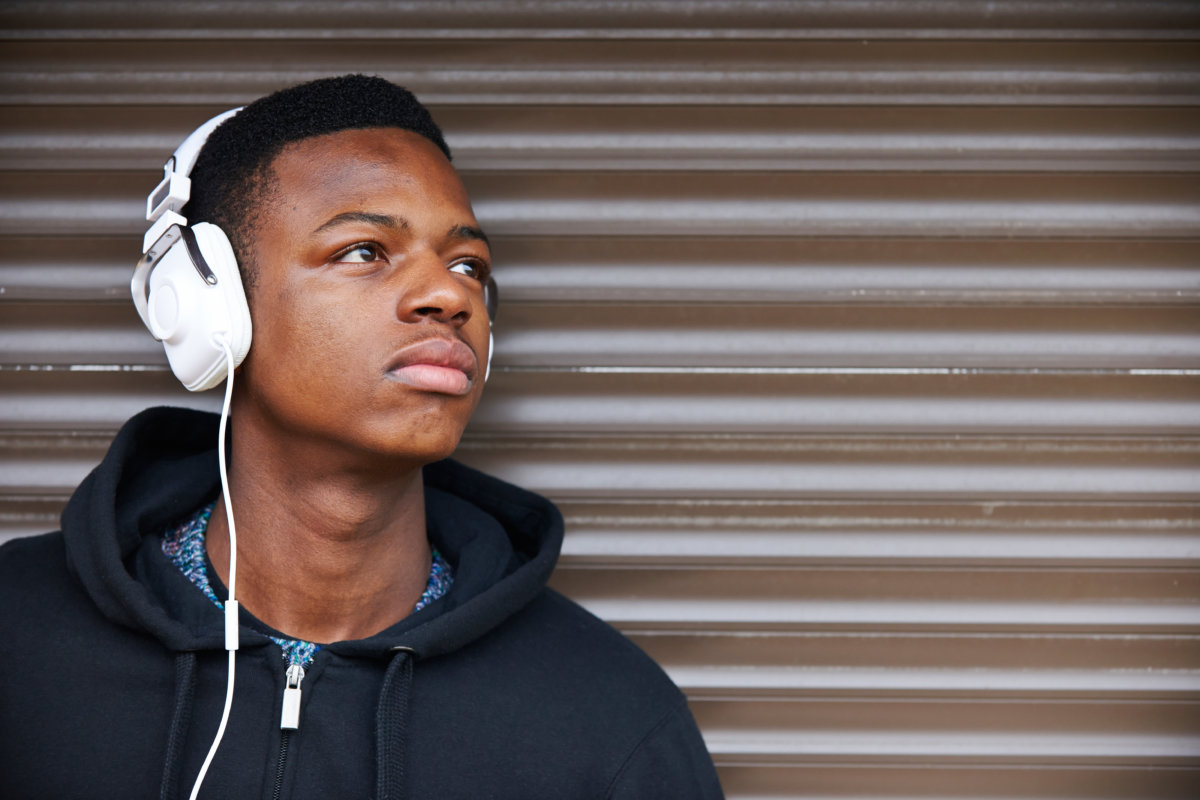 Teenage Boy Listening To Music In Urban Setting