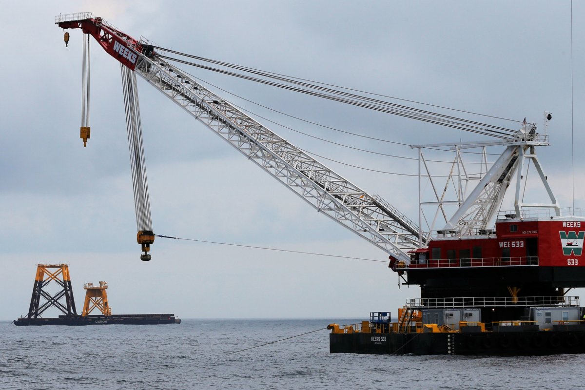 FILE PHOTO: Construction crane floats next to a barge carrying jacket support structures and a platform for a turbine for a wind farm in the waters of the Atlantic Ocean off Block Island, Rhode Island