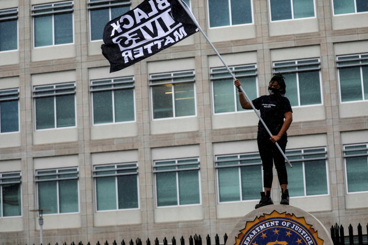 FILE PHOTO: A protester carries a Black Lives Matter flag outside the Federal Bureau of Investigation Minneapolis Division field office, days after Daunte Wright was shot and killed by a police officer, in Brooklyn Center, Minnesota