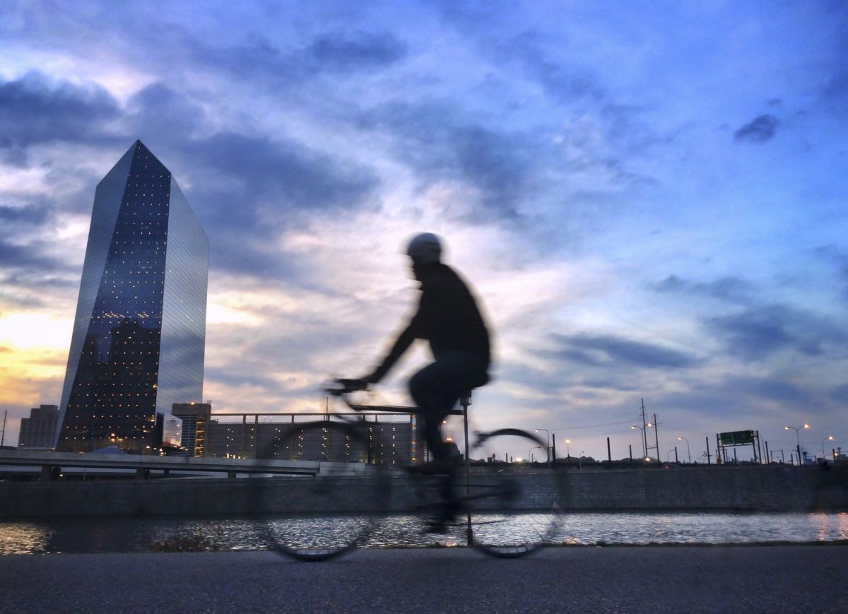 Biker on the Schuylkill River pathway at sunset with urban skyline
