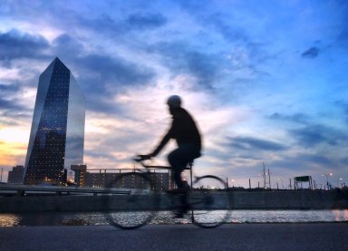 Biker on the Schuylkill River pathway at sunset with urban skyline