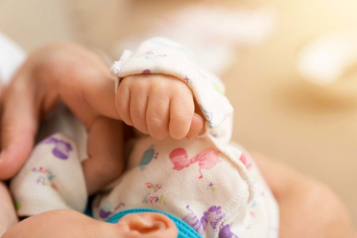 Hand of sleeping baby in the hand of mother while breastfeeding. New family and baby concept