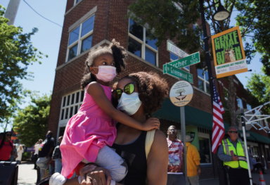 A woman holds her daughter on the corner of Greenwood and Archer during festivities ahead of the 100 year anniversary of the 1921 Tulsa Massacre in Tulsa