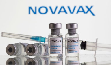 FILE PHOTO: Vials labelled “COVID-19 Coronavirus Vaccine” and syringe are seen in front of displayed Novavax logo in this illustration