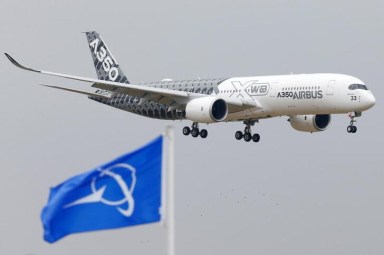 FILE PHOTO: An Airbus A350 jetliner flies over Boeing flags as it lands after a flying display during the 51st Paris Air Show at Le Bourget airport near Paris