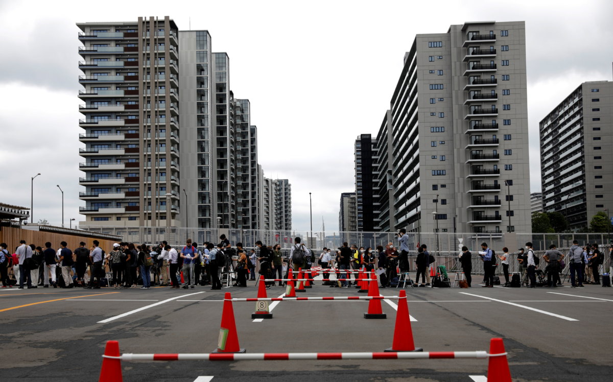 Journalists stand in a line to enter the village plaza of the Tokyo 2020 Olympic and Paralympic Village for a press tour in Tokyo