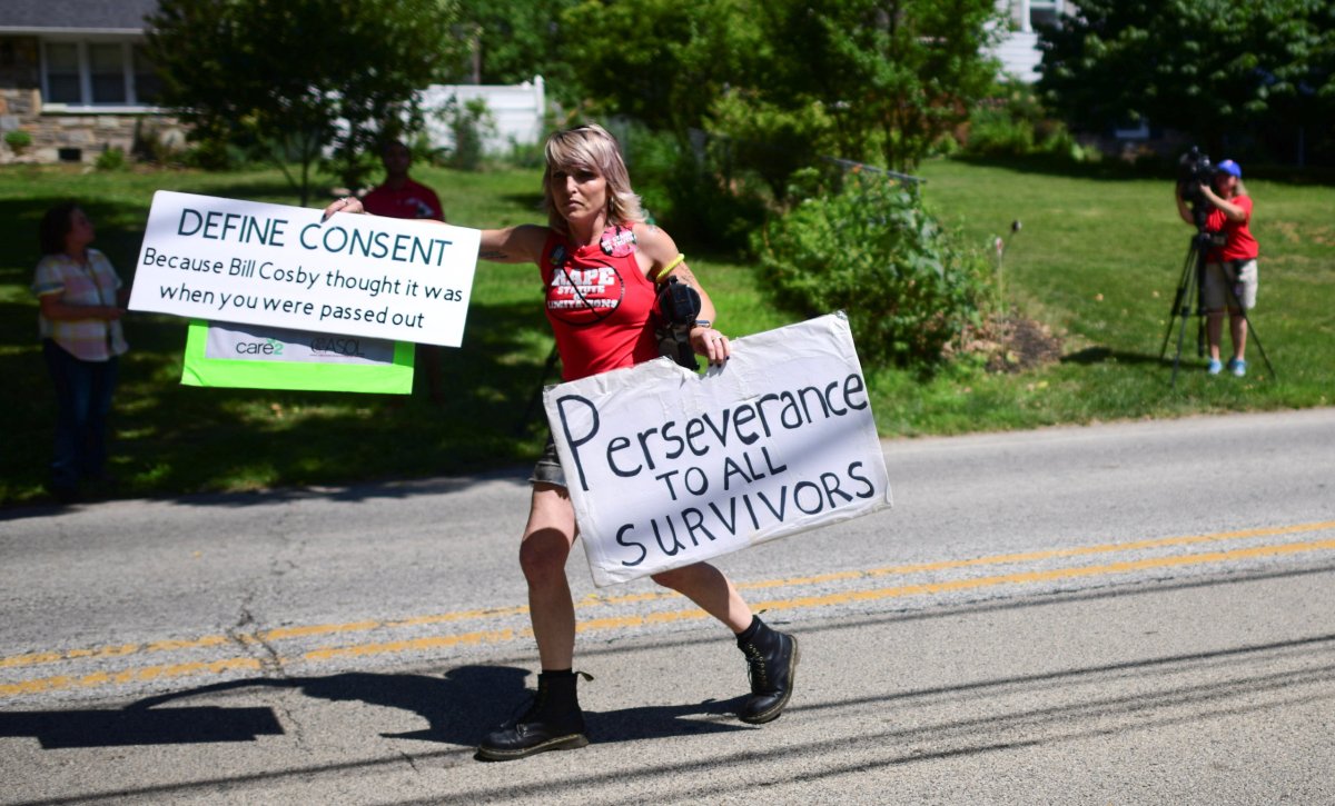 A woman carries protest signs as Bill Cosby is welcomed home after Pennsylvania’s highest court overturned his sexual assault conviction and ordered him released from prison immediately, in Elkins Park