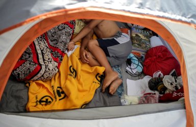 FILE PHOTO: An asylum-seeking migrant youth, who was apprehended and returned to Mexico under Title 42 after crossing the border from Mexico into the U.S., rests in a public square where hundreds of migrants live in tents, in Reynosa