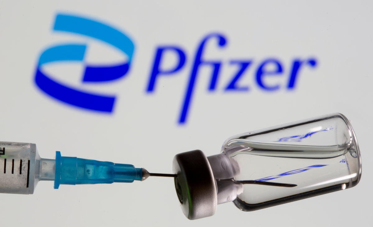 FILE PHOTO: Syringe and vial are seen in front of displayed new Pfizer logo in this illustration taken