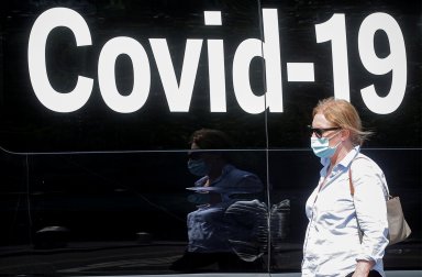 FILE PHOTO: A woman passes by a COVID-19 mobile testing van in New York