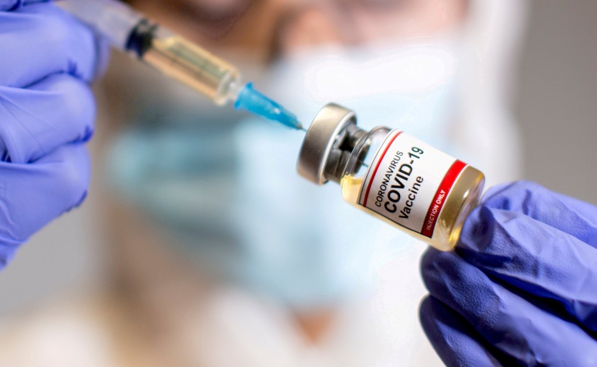 FILE PHOTO: A woman holds a medical syringe and a small bottle labelled “Coronavirus COVID-19 Vaccine