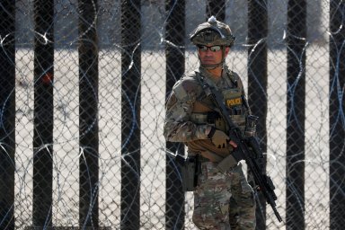 FILE PHOTO: An armed U.S. Customs and Border Patrol agent stands watch at the border fence next to the beach in Tijuana, at the Border State Park in San Diego, California