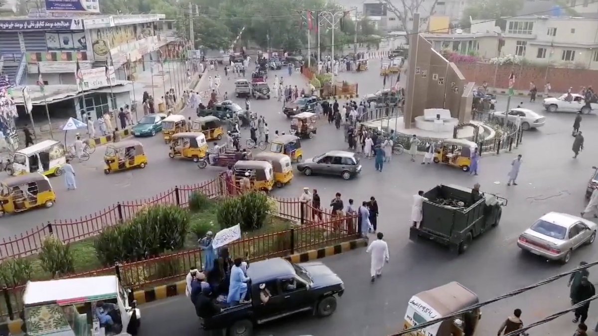 Taliban militants drive past a crowded street at Pashtunistan Square area in Jalalabad