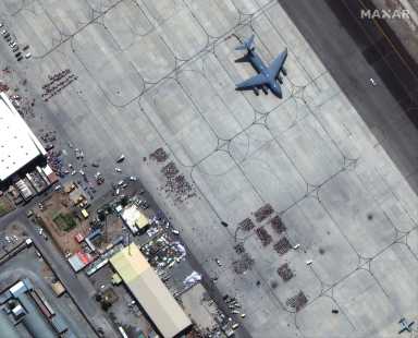 Groups of people wait on tarmac at Kabul’s airport