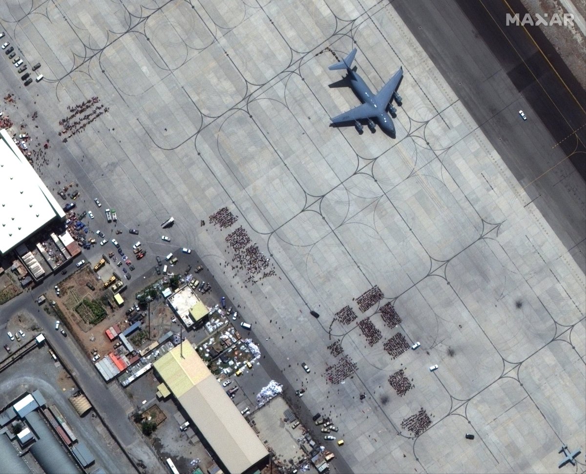 Groups of people wait on tarmac at Kabul’s airport