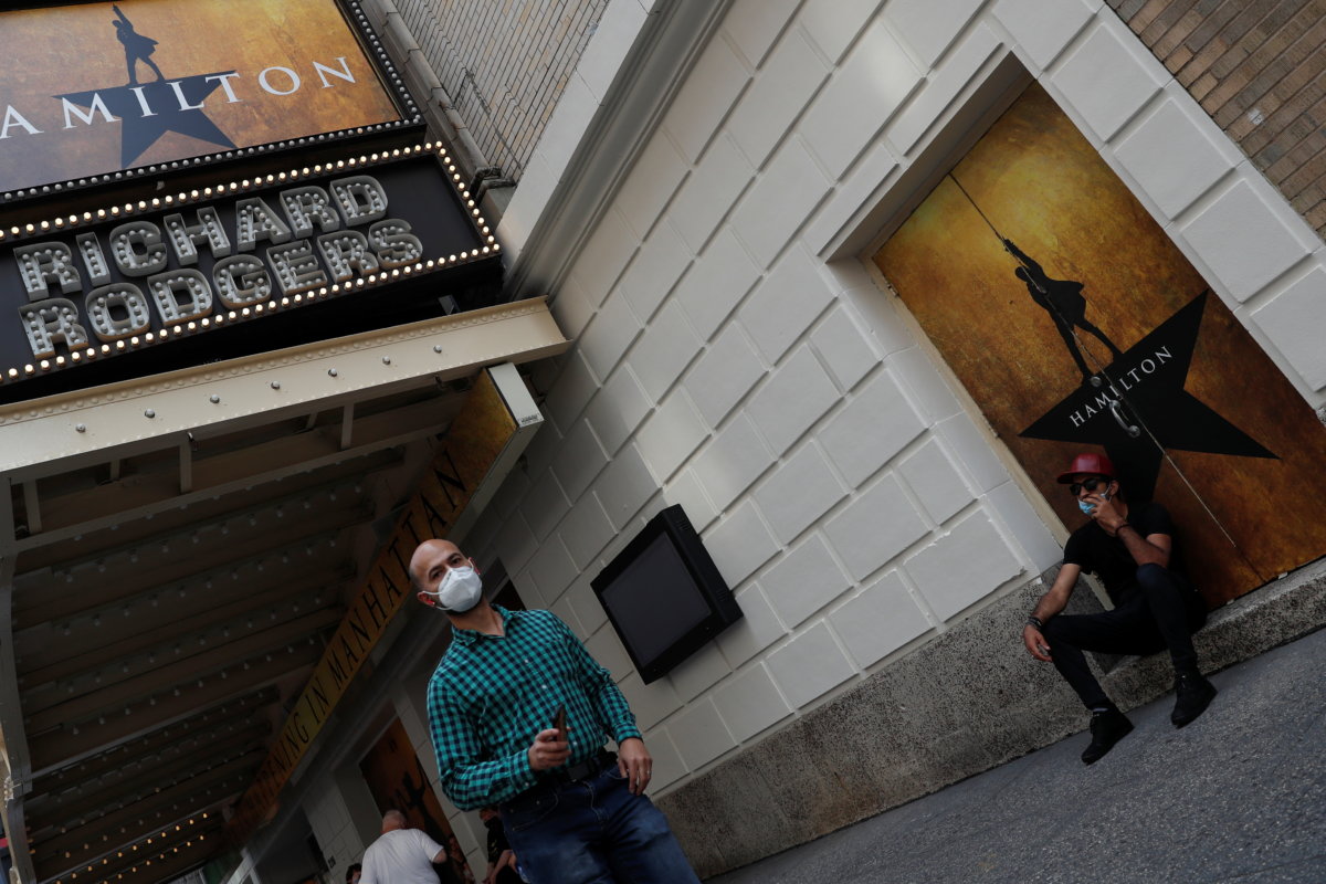 A man walks wearing a protective face mask past the marquee for the Broadway show “Hamilton” in the Times Square area of Manhattan, New York City
