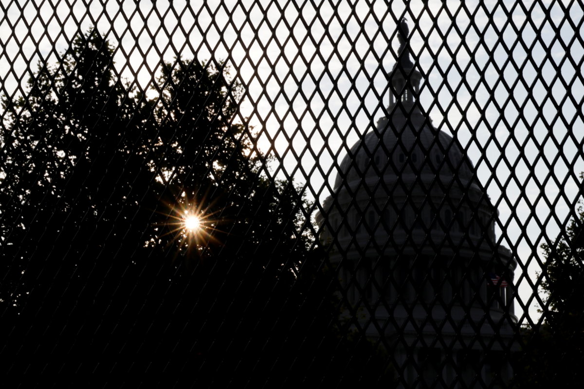 The sun rises behind the U.S. Capitol, surrounded by a security fence ahead of an expected rally Saturday in support of the Jan. 6 defendants in Washington