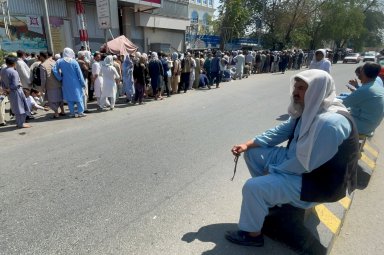 FILE PHOTO: Afghans line up outside a bank to take out their money after Taliban takeover in Kabul