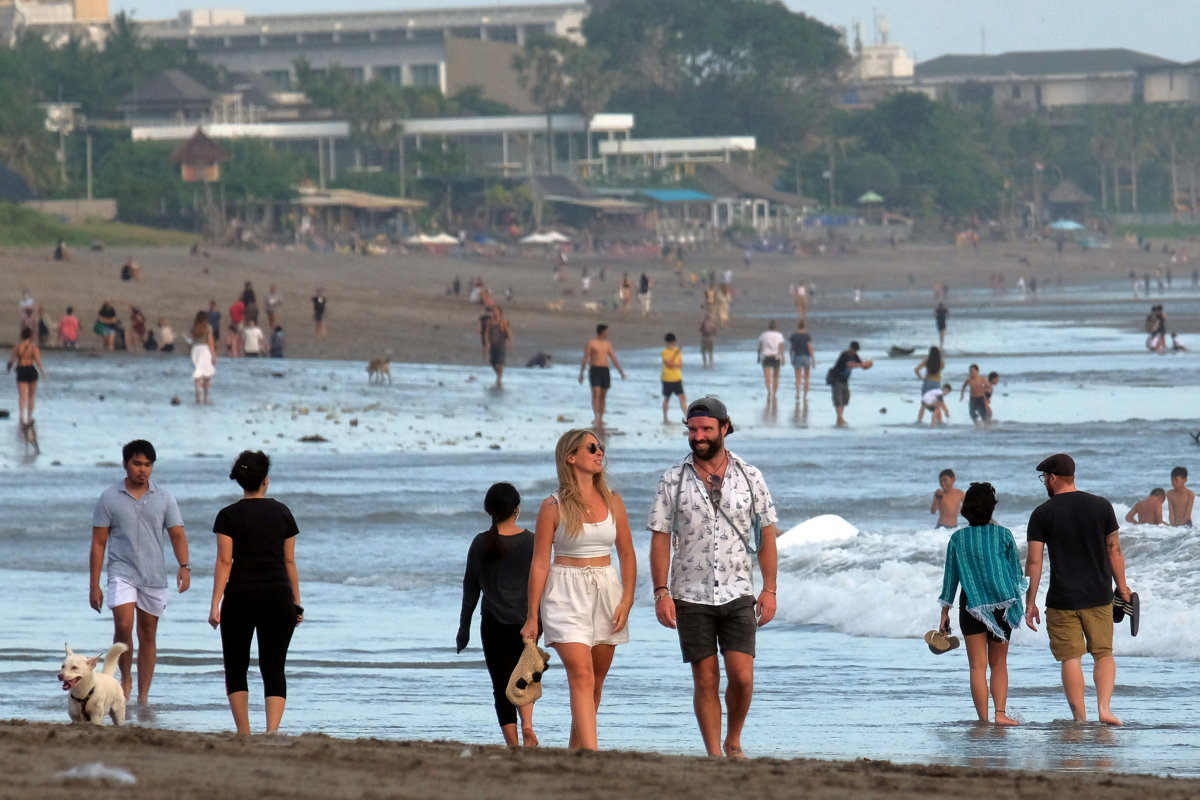 FILE PHOTO: Tourists walk on a beach as the government extends restrictions to curb the spread of coronavirus disease (COVID-19) in Badung