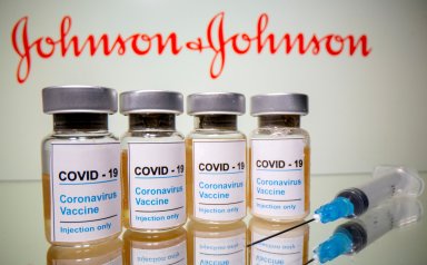 FILE PHOTO: Vials and medical syringe are seen in front of J&J logo in this illustration