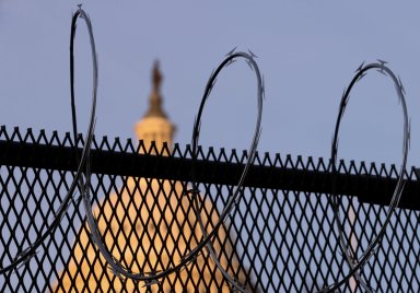 FILE PHOTO: Workers install razor wire atop the unscalable fence surrounding the U.S. Capitol in Washington