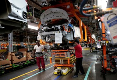 FILE PHOTO: General Motors assembly workers connect a battery pack underneath a partially assembled Chevrolet Bolt EV vehicle