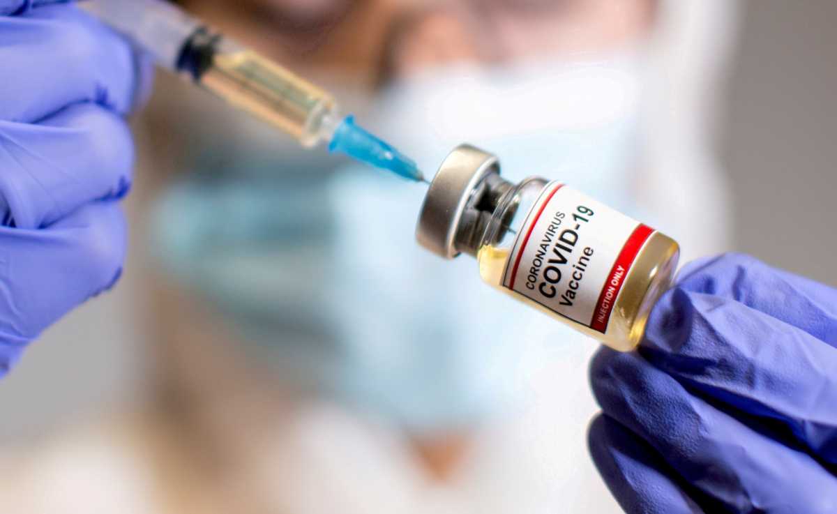 FILE PHOTO: A woman holds a medical syringe and a small bottle labelled “Coronavirus COVID-19 Vaccine