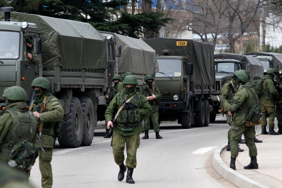 FILE PHOTO:  Armed servicemen wait near Russian army vehicles outside a Ukrainian border guard post in the Crimean town of Balaclava