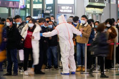 A security guard blocks an exit as he directs people to scan a QR code to track their health status at Shanghai Hongqiao Railway Station