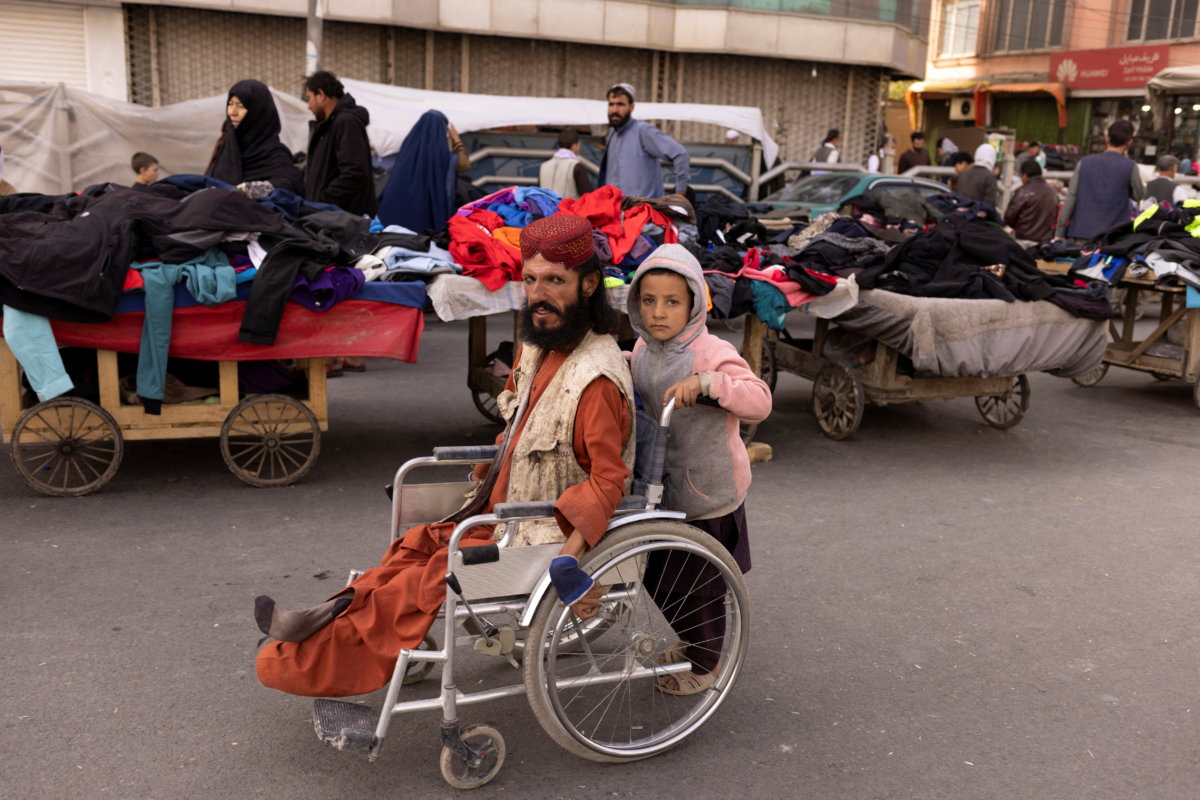 A boy pushes a man’s wheelchair on a street in Kabul
