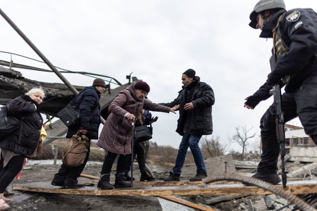 Local residents cross a destroyed bridge as they evacuate from the town of Irpin, after days of heavy shelling on the only escape route used by locals, while Russian troops advance towards the capital, in Irpin, near Kyiv