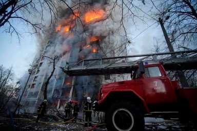 Rescuers work next to a residential building damaged by shelling in Kyiv
