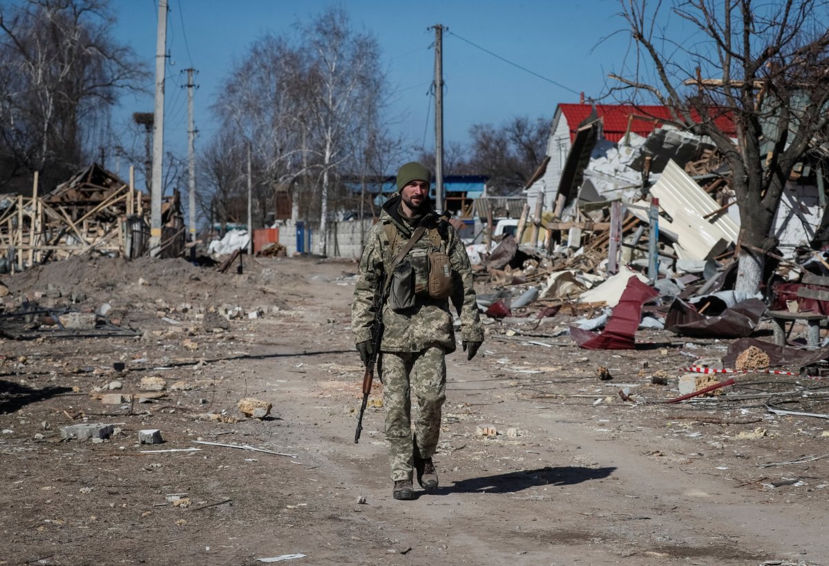 Ukrainian service member walks in a destroyed village on the front line in the east Kyiv region