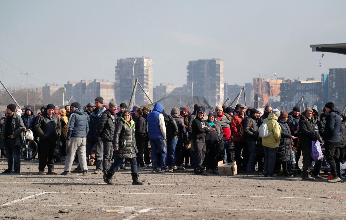People stand in a line during the distribution of humanitarian aid in the besieged city of Mariupol
