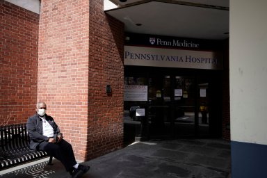 A hospital staff member wears a protective face mask against coronavirus disease (COVID-19) as he sits outside Pennsylvania hospital in Philadelphia